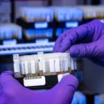 Un laborantin qui tient une boite de séquençage lors d'un test ADN
