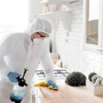 Technicien en combinaison de protection traitant une cuisine contre les cafards et autres nuisibles