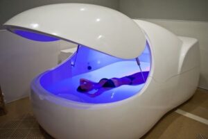 Cabine de flottaison high-tech dans un centre de flottaison, éclairée de lumière bleue violacée