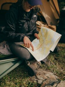 Une femme est assise dans une tente et étudie une carte lors d'un voyage de camping dans la nature.