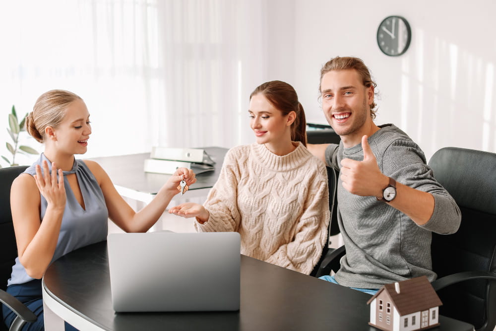 Une conseillère d'une bonne agence immobilière finalise l'achat d'un bien avec un couple heureux.